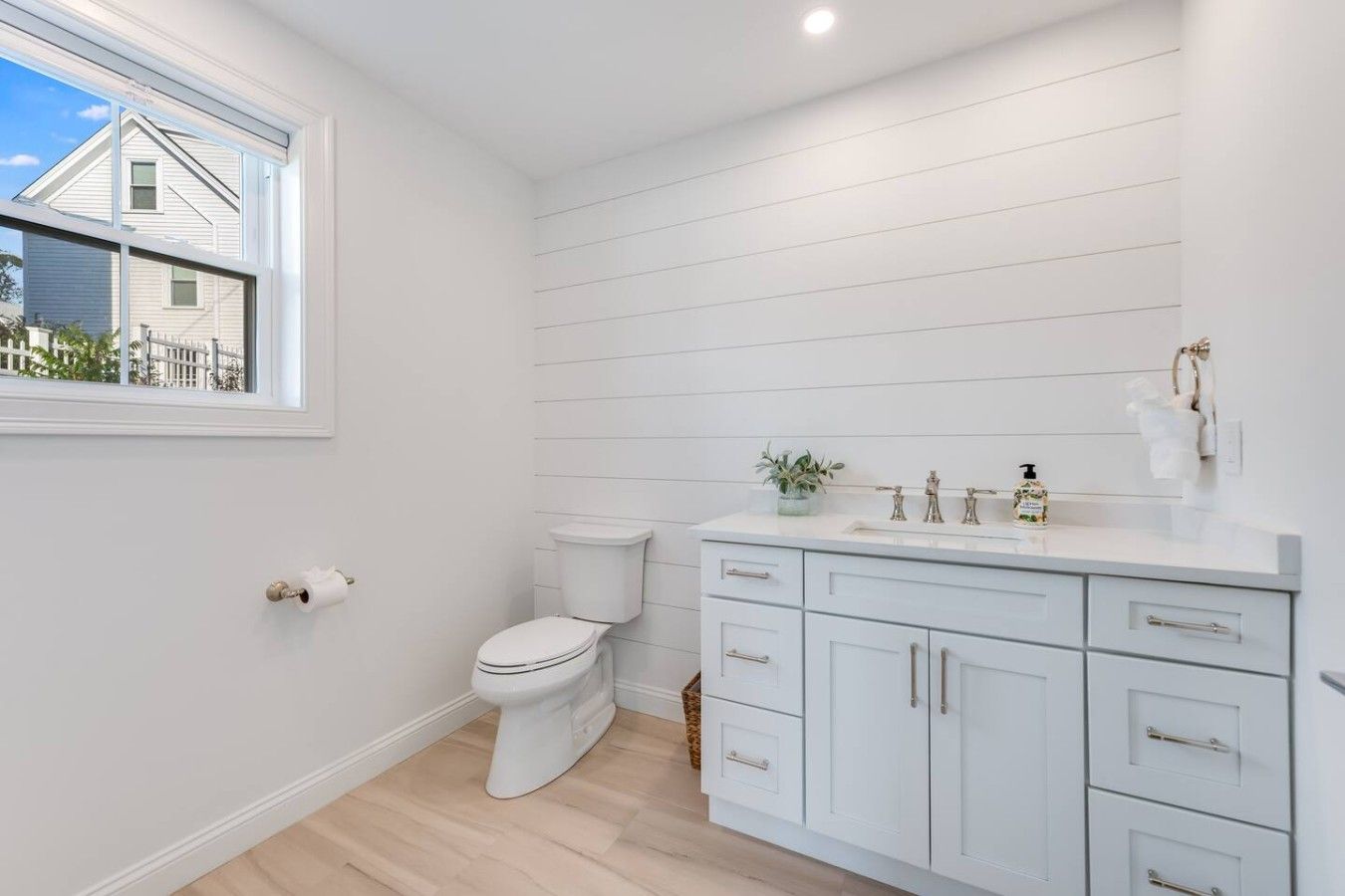 Un baño con inodoro, lavabo con espejo y ventana.