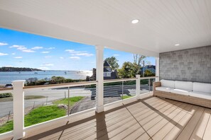 A balcony with a view of a body of water, a white sofa, and a patterned wall.
