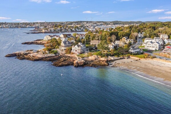 A coastal residential area with houses along the shoreline and a view of the sea.