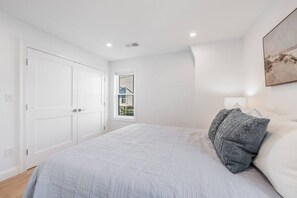 A bedroom with a bed, a window, and a door.