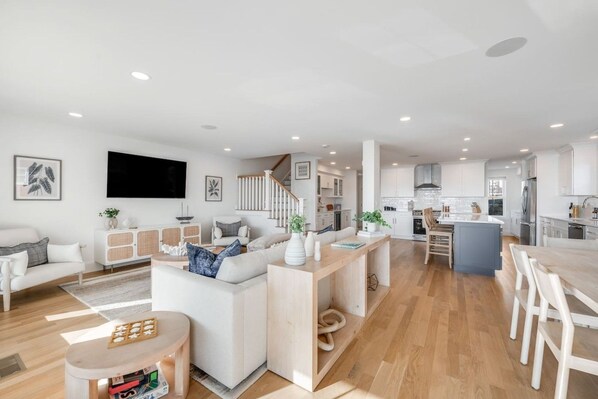 A modern open-plan living space with a kitchen, dining area, and a staircase leading to an upper level.