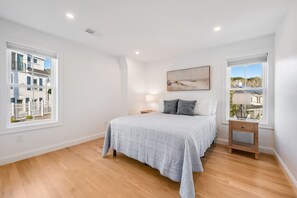 A bedroom with a bed, bedside tables, and a window with a view of buildings. - Luxury Portside Townhome Steps to Niles Beach (Gloucester)