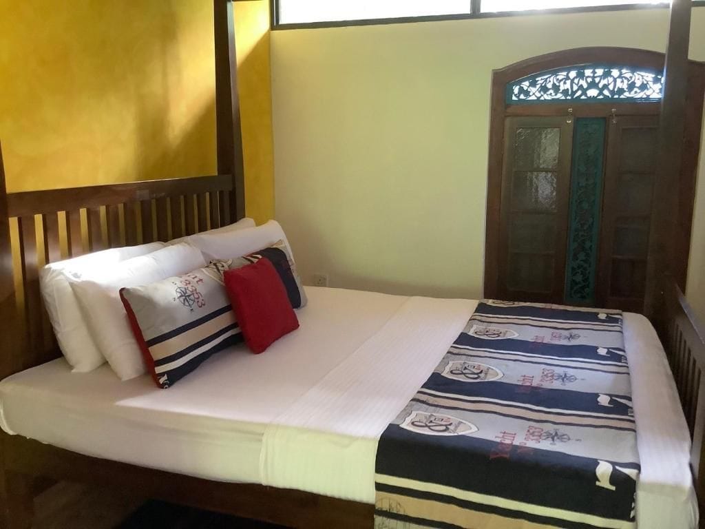 Una cama con colchón blanco, almohadas y una colcha estampada.