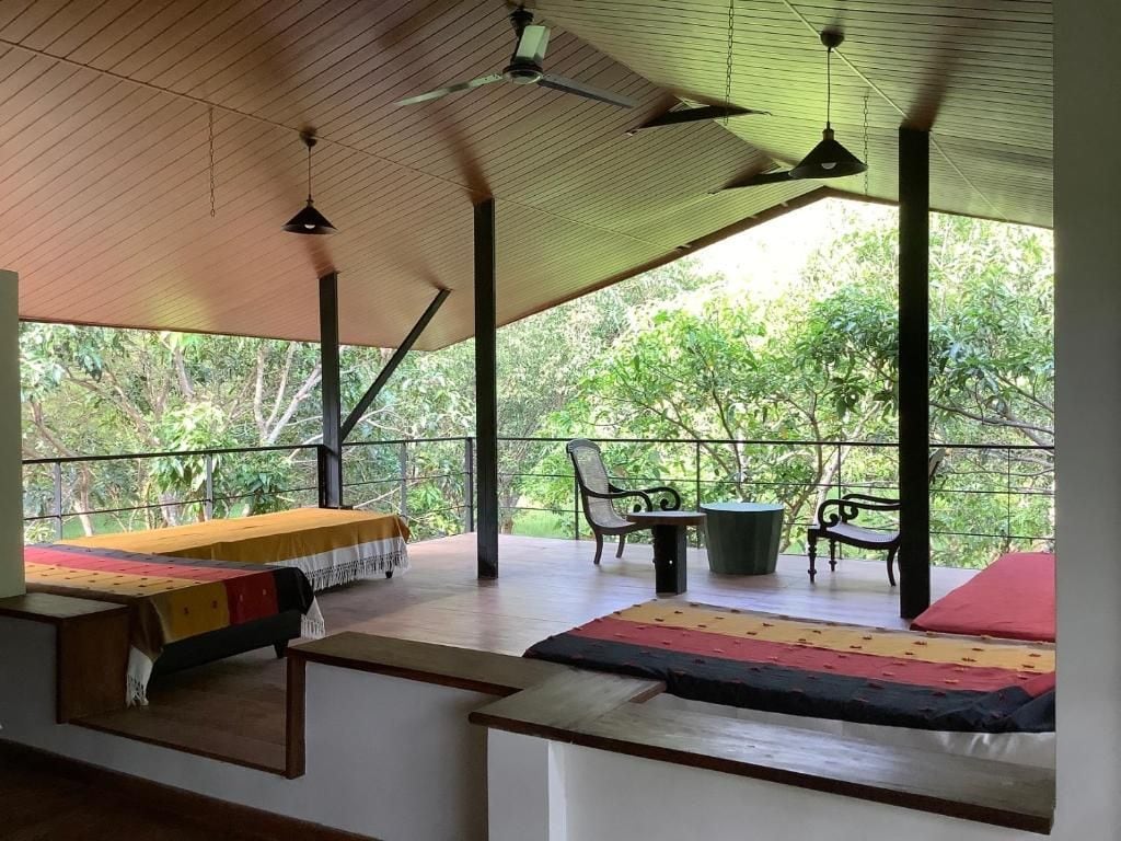 A room with a bed, a table, and chairs, with a view of greenery outside.