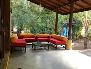 A covered outdoor seating area with a sofa and a coffee table. - Mind Body & Soul (Dambulla)