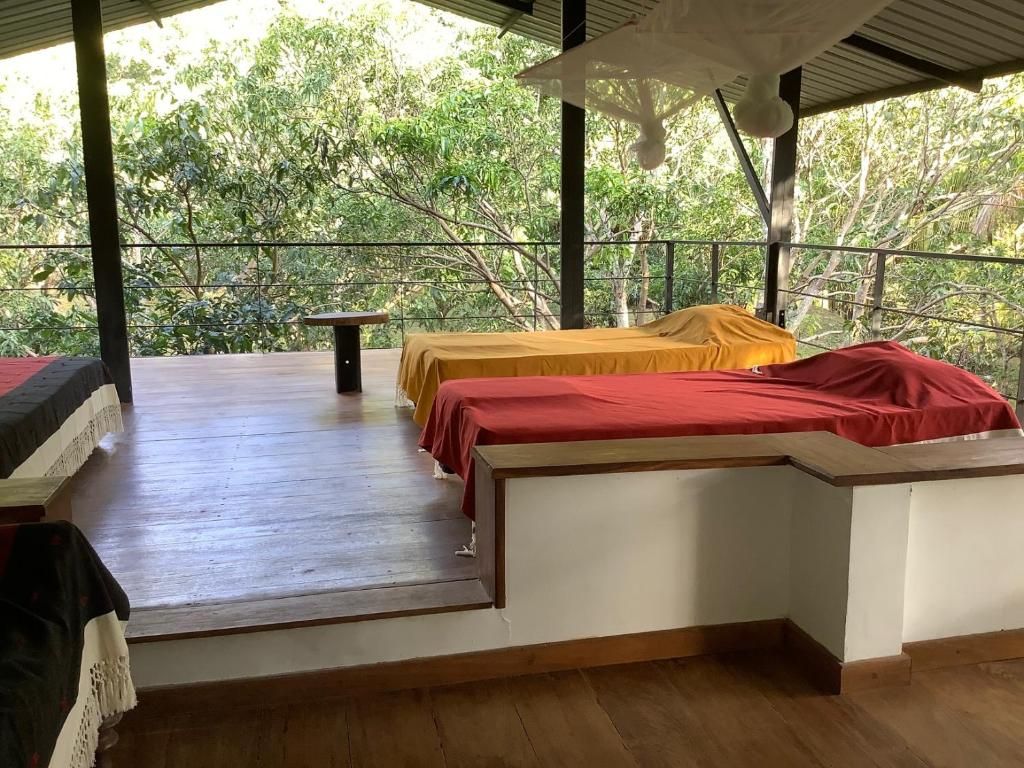A room with two beds, a table, and a view of trees.