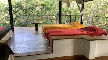 A room with two beds, a table, and a view of trees.
