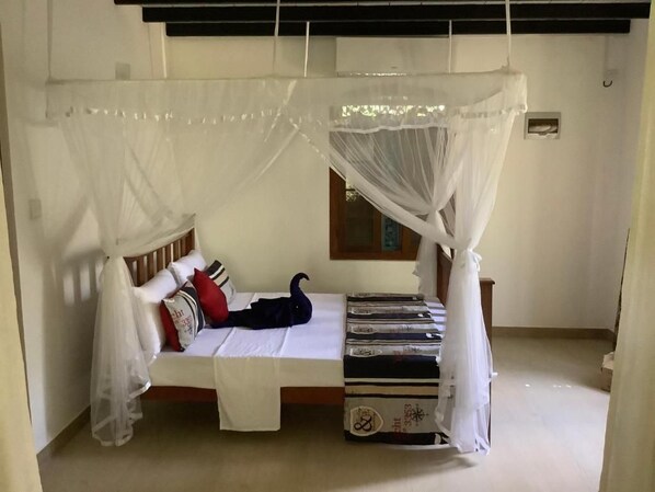 Habitación con cama bajo un dosel blanco, una ventana y un pequeño aire acondicionado de pared.