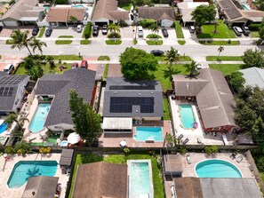 Un quartier résidentiel comprenant plusieurs maisons, des panneaux solaires et des piscines.