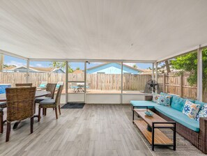 Une terrasse couverte comprenant un coin repas, un canapé et un ventilateur.