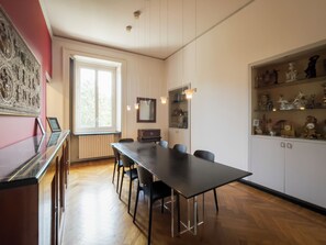 A dining area with a long table, chairs, a window, and a cabinet with decorative items. - Vrbo Property (Torino)