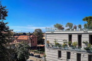 A building with multiple balconies, some with plants, and a clear blue sky in the background. - Vrbo Property (Torino)
