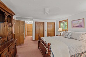 Une chambre avec un grand lit, une armoire en bois et un tableau accroché au mur.