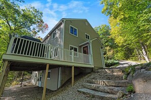 A two-story house with a deck, surrounded by trees and a stone staircase. - Waterfront 4BR Lake House l Private Dock & Views (Harrison)