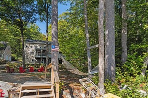 A wooden deck with a hammock, red Adirondack chairs, and a flag. - Waterfront 4BR Lake House l Private Dock & Views (Harrison)