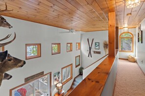 A hallway with wooden ceilings, framed pictures, and mounted deer antlers. - Waterfront 4BR Lake House l Private Dock & Views (Harrison)