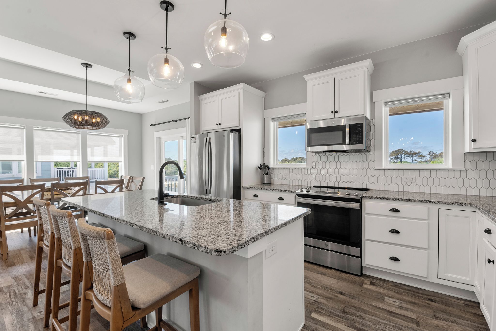 A modern kitchen with a large island, stainless steel appliances, and pendant lighting.