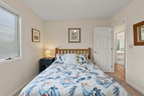 A bedroom with a bed, a nightstand, a lamp, a door, and two framed pictures on the wall. - Private Pool, Hot Tub | Shuffleboard Table | Dogs OK (Corolla)