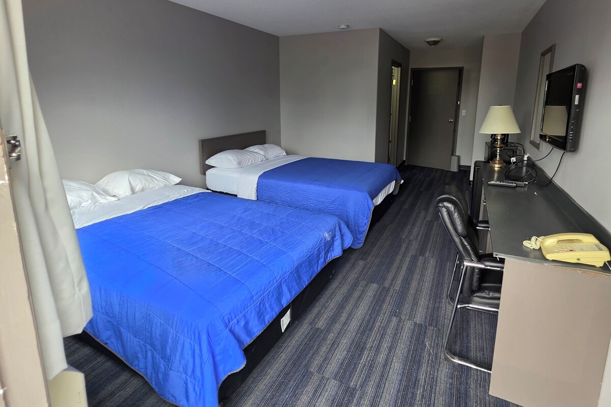 A hotel room with two beds, a desk, a telephone, and a television.