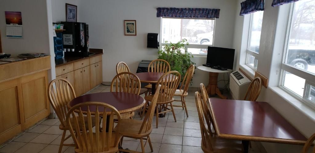 Zona pranzo con sedie e tavoli in legno, una macchina per caffè, una televisione e una finestra vista strada.