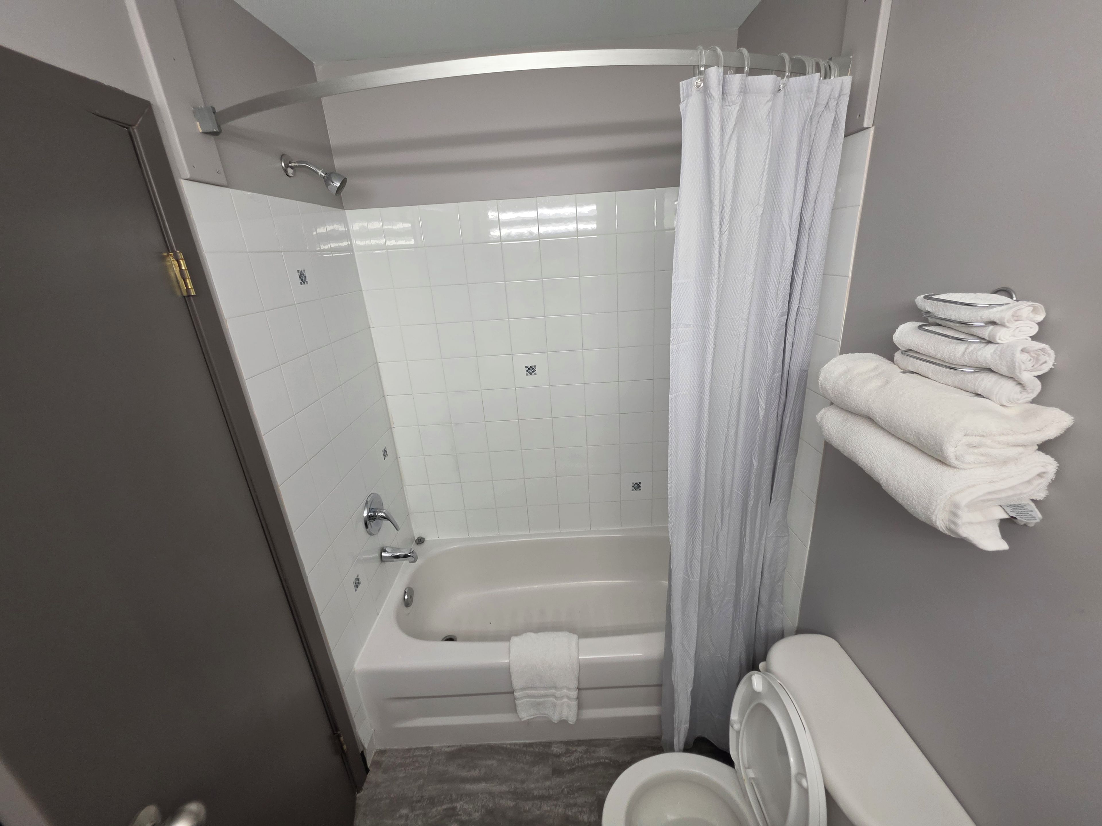 A bathroom with a bathtub, toilet, and a towel rack with towels.