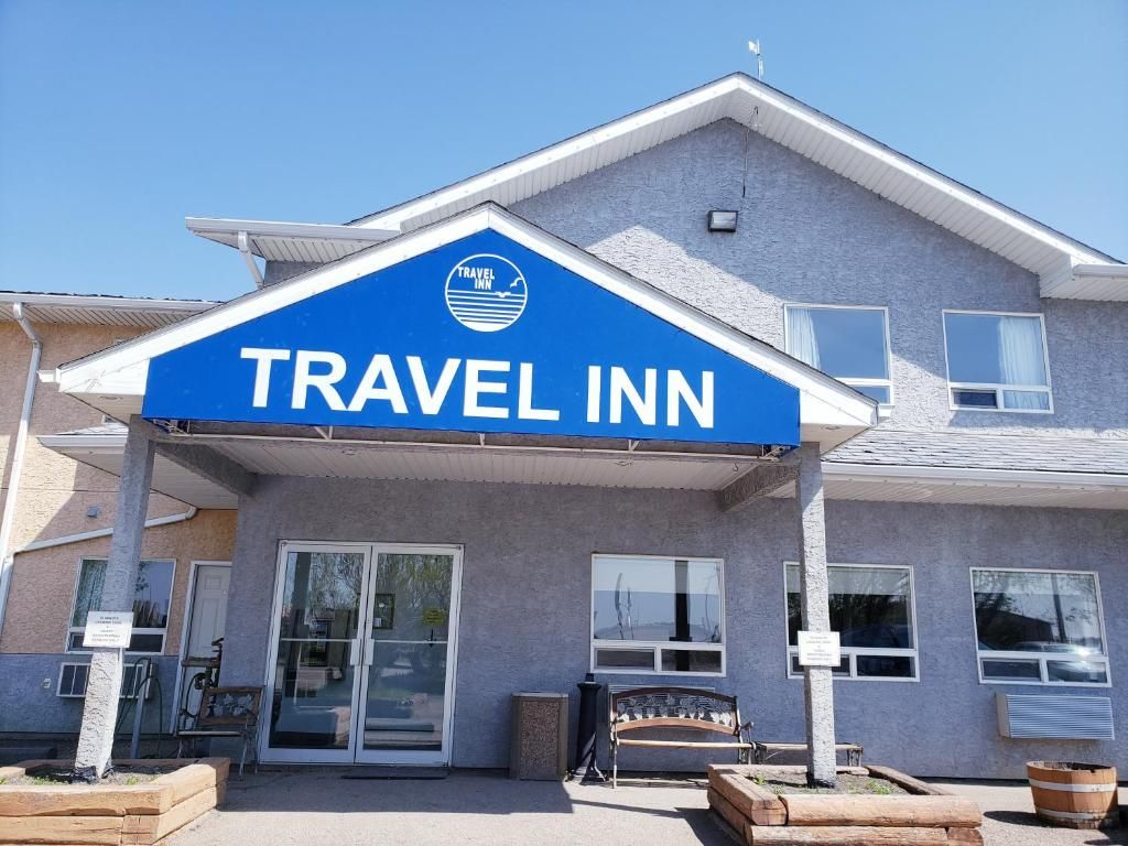 A Travel Inn hotel with a prominent blue sign, a covered entrance, and a bench outside.