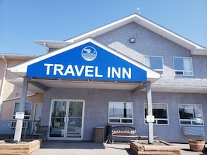 Hotel Travel Inn amb un cartell blau destacat, entrada coberta i una panxa de gos a l'exterior.
