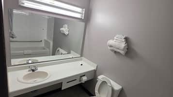 Un bagno con un lavandino, uno specchio e un WC bianchi. È presente un porta asciugamani a parete e un cestino.