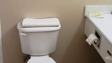 A bathroom with a toilet, a towel rack with folded towels, and a toilet paper holder.