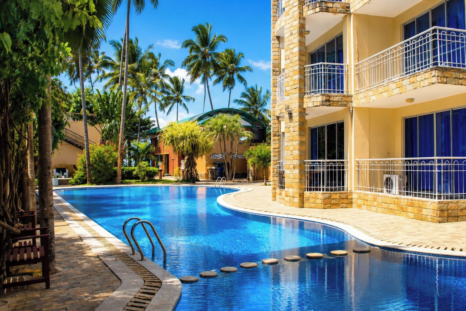 A swimming pool with a stone building adjacent to it, featuring balconies with railings.