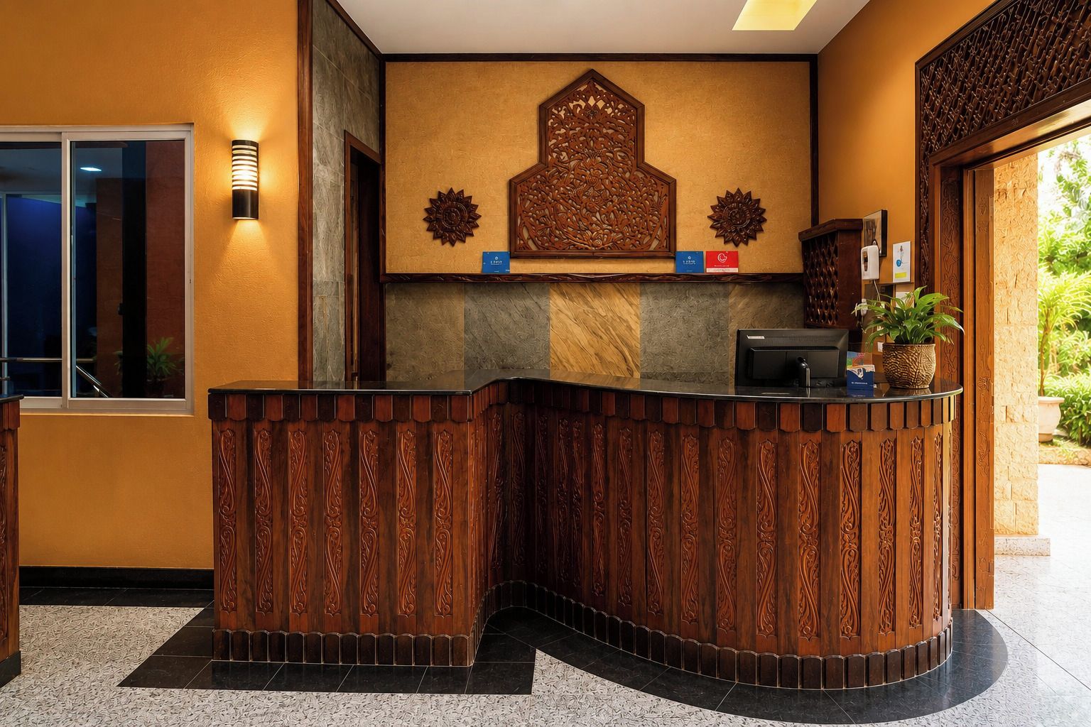 A reception desk with intricate wood carvings, a wall-mounted decorative piece, and a potted plant.