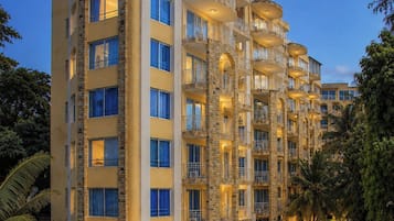 Un hotel de varios pisos con balcones, piscina y abundante vegetación.