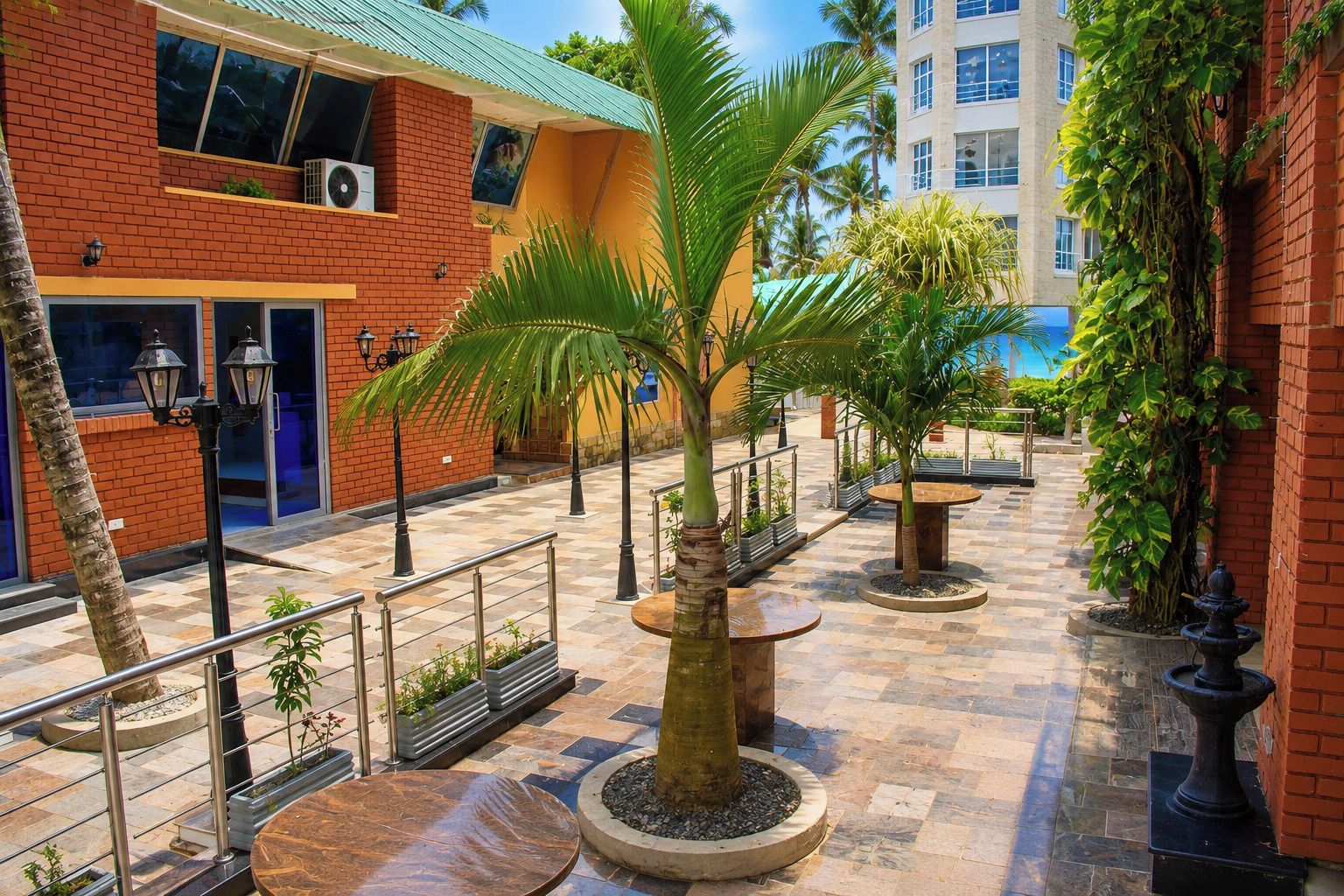 Un patio con una palmera, mobiliario exterior y un edificio de fachada de ladrillo.