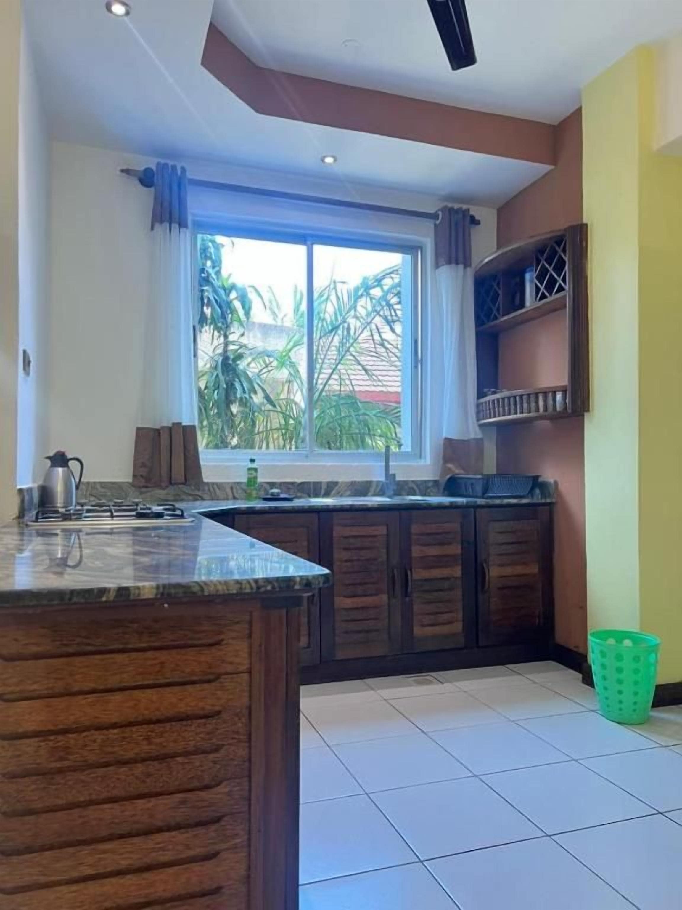Una cocina con un ventanal grande, armarios y una cesta verde.