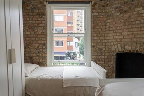 A bedroom with a brick wall, a window, and a bed. - Luxury City Apartment in the Heart of Farringdon (London)
