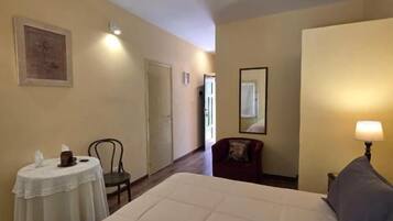 Una habitación de hotel con una cama grande, una mesita redonda pequeña, una silla y una lámpara.