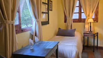 Una habitación con una cama, una mesa, una silla y una lámpara.