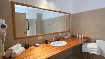A bathroom with a wooden vanity, a large mirror, a sink, and a towel rack.