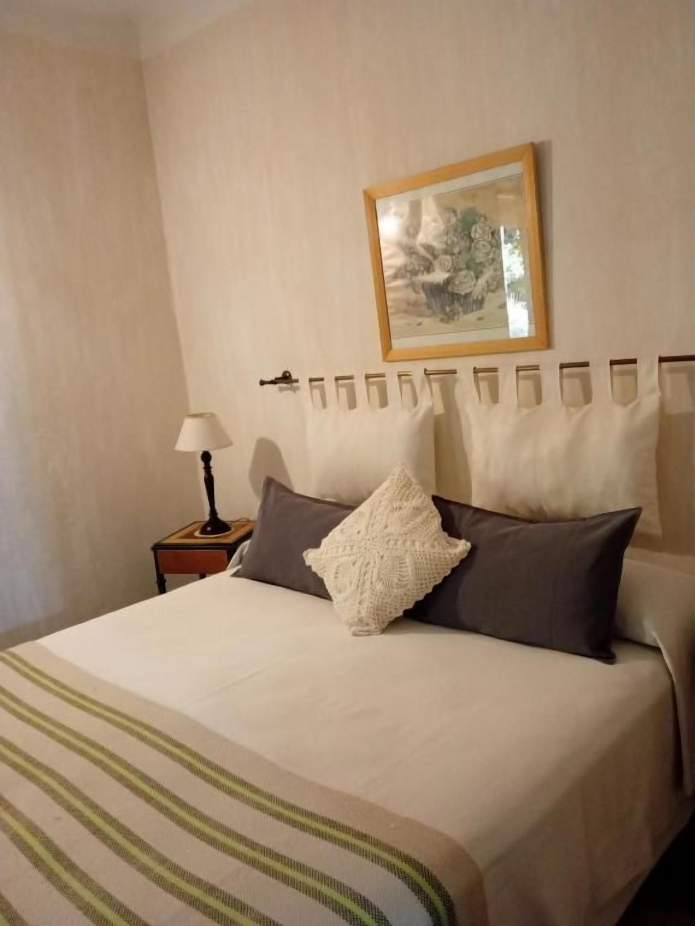 Habitación de hotel con cama, mesita de noche, lámpara y un cuadro en la pared.