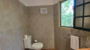 Une salle de bain avec des toilettes, un lavabo et une fenêtre.