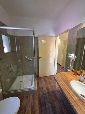 A modern bathroom with a glass-enclosed shower, a wooden vanity with a sink, and a mirror.
