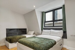 Une chambre avec deux lits, une fenêtre avec des rideaux et un plafond en pente.