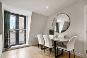 A dining area with a table and chairs, a large mirror, and a window with curtains. - 1BR Flat 1 Min from Finsbury Park Station (London)