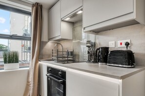 A modern kitchen with a built-in oven, a kettle, and a toaster on the counter. - Deluxe Studio | 1 Minute to Finsbury Park Station (London)