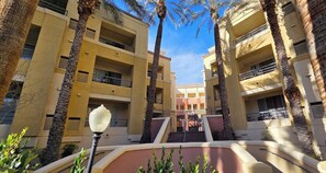 A multi-story building with balconies, palm trees, and a central staircase. - Luxury Las Vegas Strip!  1BR Private Residences Condo ~ 24/7 Pool 1-08 (Las Vegas)