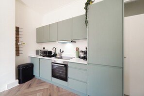 A modern kitchen with light blue cabinets, a stainless steel sink, and a built-in oven. - Beautiful Modern 2 Bed in Maida Vale (London)
