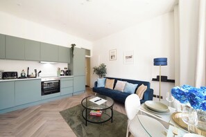 A modern living space with a kitchen, dining area, and a sofa. - Beautiful Modern 2 Bed in Maida Vale (London)