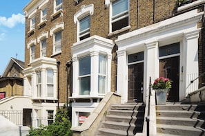 A row of traditional brick townhouses with white trim, multiple windows, and a front door. - Beautiful Modern 2 Bed in Maida Vale (London)