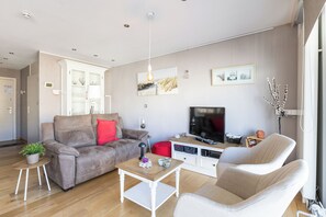 Ein modernes Wohnzimmer mit einer Couch, einem Couchtisch, einem Fernseher und einem Bücherregal.