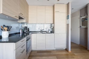 A modern kitchen with light wood cabinetry, a stainless steel sink, and a built-in oven. - Wielingerbank F 0405* (Nieuwpoort)